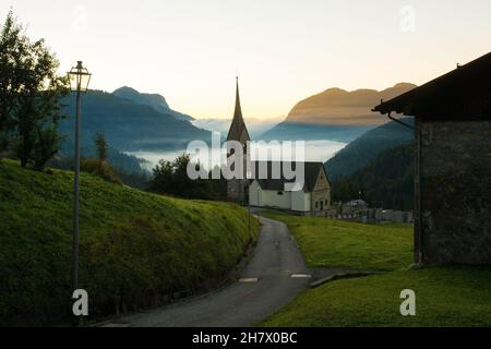 Niedrige Wolken während der Morgengrauen über dem Sauris-Tal in der Nähe des Alpendorfes Sauris di Sopra, Provinz Udine, Friaul-Julisch Venetien, Nordostitalien. Spät Stockfoto