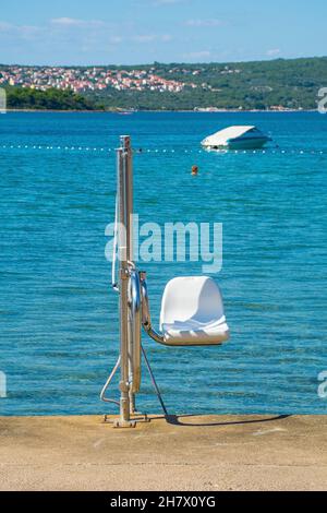 Ein Sessellift, der behinderten Menschen am Wasser von Punat auf der Insel Krk in der Provinz Primorje-Gorski Kotar in Westkroatien hilft, ins Meer zu gelangen Stockfoto