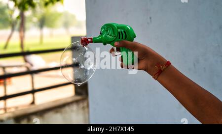 Nahaufnahme einer Seifenblasenpistole. Kleines Kind hält eine Luftblasenpistole im Freien. Stockfoto