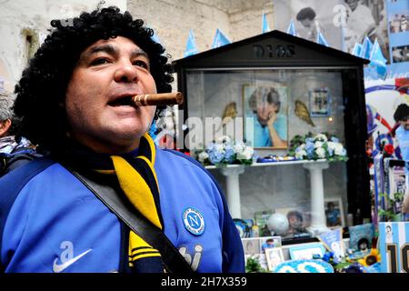 Napoli, Italien. 25th. November 2021. Ein Boca Juniors Fan mit einer Zigarre im Mund feiert am Wandgemälde von Diego Armando Maradona im Spanischen Viertel zum Jahrestag des ersten Jahres seit seinem Tod. Napoli, Italien, 25. November 2021. (Foto von Vincenzo Izzo/Sipa USA) Quelle: SIPA USA/Alamy Live News Stockfoto