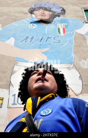 Napoli, Italien. 25th. November 2021. Ein Boca Juniors Fan mit einer Zigarre im Mund feiert am Wandgemälde von Diego Armando Maradona im Spanischen Viertel zum Jahrestag des ersten Jahres seit seinem Tod. Napoli, Italien, 25. November 2021. (Foto von Vincenzo Izzo/Sipa USA) Quelle: SIPA USA/Alamy Live News Stockfoto