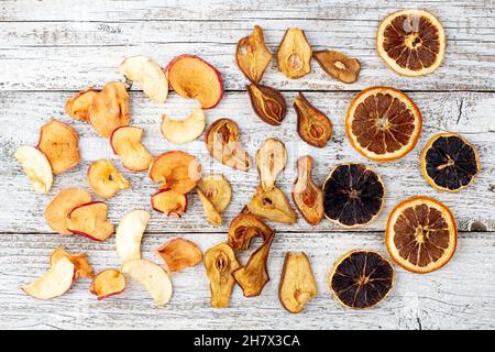 Muster eines Stapels getrockneter Birnen Zitrus und Äpfel in Scheiben auf weißem Holzhintergrund. Getrocknete Fruchtchips. Gesunde Ernährung. Draufsicht Stockfoto