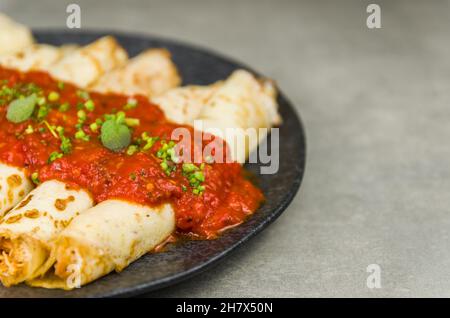 Brasilianische Pfannkuchen mit Huhn, Tomatenbolognese-Sauce, gerollte Pfannkuchen. Stockfoto