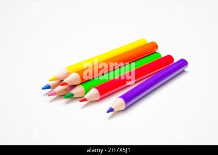 Kindheit, zurück zur Schule, Bildung, Kreativität. Sieben Stifte in hellen Regenbogenfarben auf weißem Schreibtischhintergrund. Stockfoto