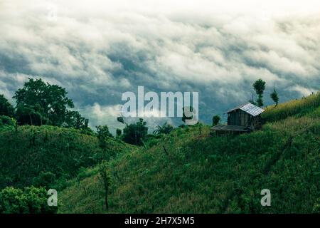 Bild des Bandarban-Hügeltraktes, Bangladesch. Natürliche Hügellandschaft mit Wolken. Haus auf der Spitze eines Berges. Stockfoto