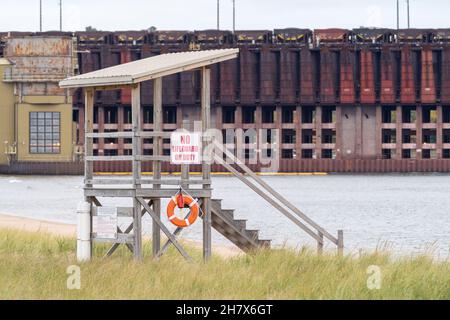 Marquette, Michigan - 20. Oktober 2021: Rettungsschwimmerstation in Marquette Michigan, von einem nahe gelegenen Strand aus gesehen, mit den Erzdocks im Hintergrund Stockfoto