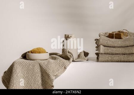 Handgemachte Bio-Seife auf Waffelwäsche-Handtüchern, Meeresschwamm und beigefarbenem Seifenspender. Badezimmer Null Abfall Zubehör. Tägliche Körperpflege, Spa und Wellness Stockfoto