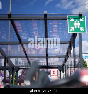 Kongen, 23. Mai 2021: Firmenlogo Kaufland in einer überdachten Einkaufswagenhalle. Schieben Sie die Wagen, die sich im Glas darüber spiegeln. Schild „Abholstelle“ Stockfoto