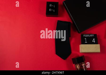 Schwarze Krawatte, Geschenkbox, Mann Parfüm auf rotem Hintergrund. Stockfoto