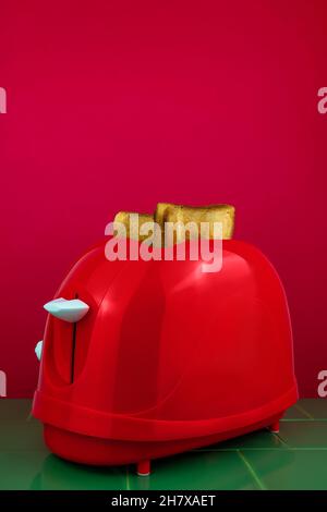 Roter Toaster mit knusprigen, frischen Brotscheiben in der Küche mit grünen Kacheln. Morgen Toast Frühstück Idee kreativen Minimalismus Konzept. Bunte Yammy Essen backg Stockfoto