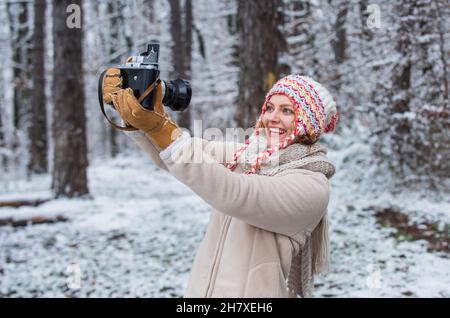 Wohlfühlen. Spaß im Freien verschneiten Wald. Kaltes Wetter bringt gute Laune. Bereit für Wettervorhersage. Expedition. Winter-Mädchen mit Vintage-Kamera Stockfoto