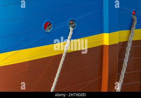 Aus zwei Löchern im bunten Bogen entsteht ein Paar Seile, mit denen eine Nachbildung von HMS Endeavour im Hafen festgemacht wurde. Stockfoto