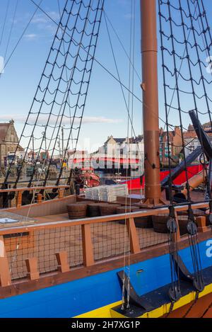 Eine Nachbildung der HMS Endeavour, die im Hafen vertäut ist. Gebäude und eine Brücke können durch die Takelage gesehen werden und es gibt einen Anker auf dem Deck. Stockfoto