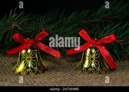 Weihnachtsglocken Spielzeug und Zweig von weihnachtsbaum auf einem Sackleinen Hintergrund Stockfoto