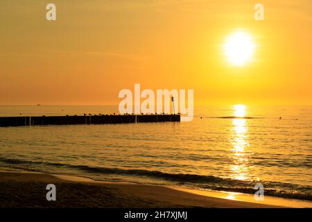Die Sonne steht noch über dem Horizont. Dieses malerische Phänomen wurde vom Strand in Kolobrzeg, Polen aus beobachtet. Stockfoto