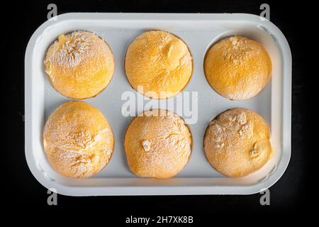 Makro-Nahaufnahme des im Laden gekauften kalten gefrorenen Eiscreme gefüllt Mochi Reiskuchen Japanisches Dessert mit Mango oder Passionsfrucht tropischen Geschmack und Stärkepulver Stockfoto