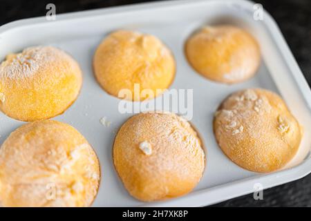 Makro-Nahaufnahme von im Geschäft gekauftem gefrorenem Eis gefüllter Mochi-Reiskuchen Japanisches Dessert mit Mango- oder Passionsfrucht-Tropengeschmack und Stärkepulver Stockfoto