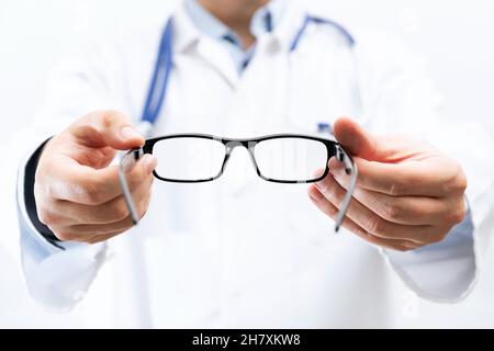 Augenarzt, Okulist in der Klinik. Optiker hält eine Brille, um es auszuprobieren Stockfoto