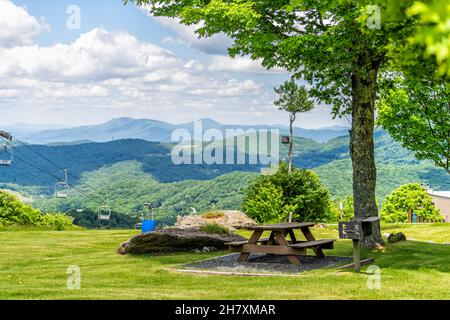 Sugar Mountain Ski Resort Stadtpark mit idyllischer Picknick-Tischbank unter einem Baum und Blick auf die Skipiste und die wunderschöne grüne North Carolina Blue Rid Stockfoto