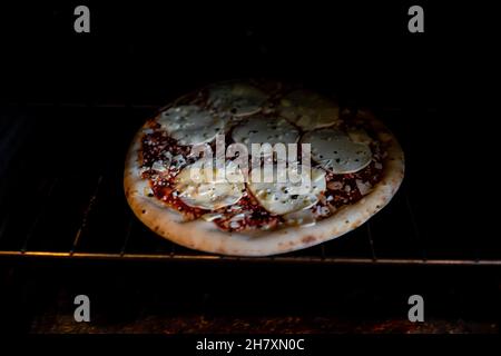 Im Inneren Ofen mit Rack und hausgemachte ganze Pizza Mozzarella Provolone Käse und bestreut rote Tomatensauce Nahaufnahme als italienische Küche Küche Backen Kochen Stockfoto