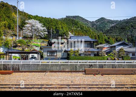 Gero Onsen, Japan Dorfhäuser Blick vom Zug in der Präfektur Gifu mit Bahngleisen und Bergblick im Frühling Frühling tagsüber mit Kirsche Stockfoto