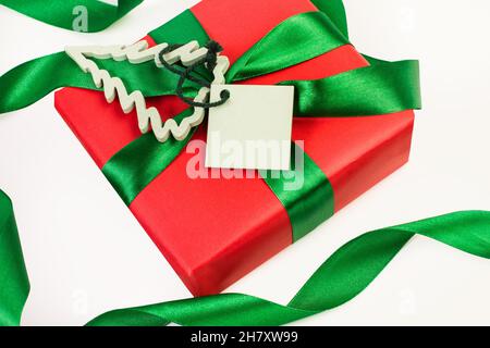 Ein rotes weihnachtsgeschenk mit einem Etikett auf weißem Hintergrund in der Draufsicht Stockfoto