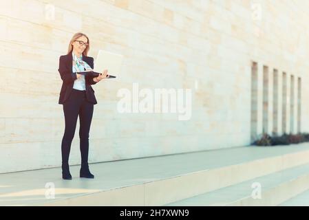 Junge Geschäftsfrau, die außerhalb des Büros am Laptop arbeitet, Erfolgskonzept Stockfoto