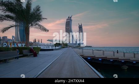 Lusail Corniche am Yachthafen in Lusail City, Katar, Sonnenuntergangsaufnahme, die Menschen zeigt, die auf der Promenade mit Skyline im Hintergrund spazieren und sitzen Stockfoto