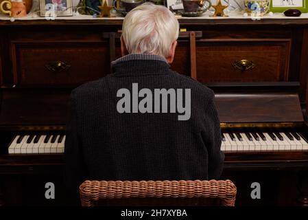 Reifer Mann spielt Klavier als Hobby, das er von der Kamera wegsieht Stockfoto