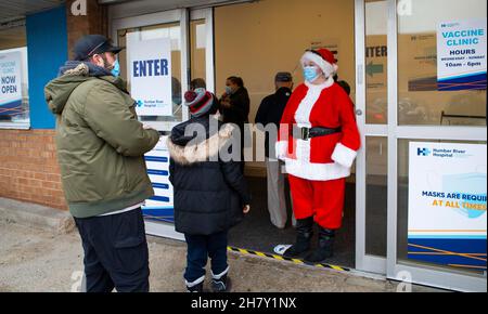 Toronto, Kanada. 25th. November 2021. Eine Frau, die als Weihnachtsmann gekleidet ist, begrüßt am 25. November 2021 ein Kind am Eingang einer Impfklinik in Toronto, Kanada. Die Stadt Toronto begann am Donnerstag mit der COVID-19-Impfung für Kinder im Alter von 5 bis 11 Jahren, die Termine bestätigt haben. Quelle: Zou Zheng/Xinhua/Alamy Live News Stockfoto