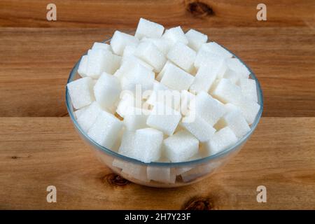 Weiße Zuckerwürfel in einer Schüssel auf Holzhintergrund Stockfoto