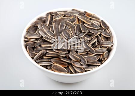 Schwarze Sonnenblumenkerne in einer Schüssel auf weißem Hintergrund Stockfoto