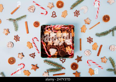 Draufsicht Hintergrund von Weihnachtsbonbons in der Metallbox und auf der blauen Oberfläche ringsum. Viele verschiedene Sorten von Weihnachtskeksen, Süßigkeiten, Süßigkeiten Stockfoto