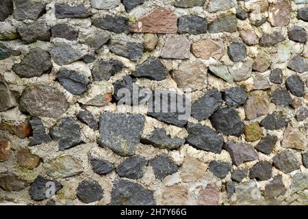 Flusssteinwände mit Zementkleber für einen natürlichen, nuancierten Hintergrund Stockfoto