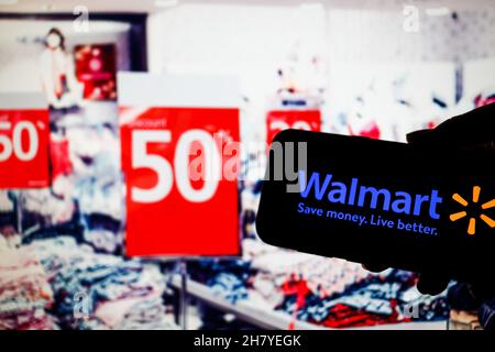 Polen. 24th. November 2021. In dieser Fotobilder ist ein Walmart-Logo auf einem Smartphone und einem Kaufhaus mit einer Vielzahl von Werbebannern im Hintergrund zu sehen. Kredit: SOPA Images Limited/Alamy Live Nachrichten Stockfoto