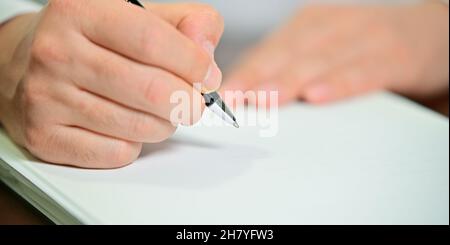 Die Hand des Geschäftsmanns hält weißes Papier und einen Stift mit Kopierplatz Stockfoto