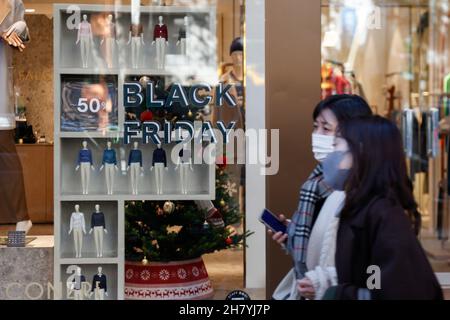 Fußgänger kommen am 26. November 2021 in Tokio, Japan, an einem Schild mit der Aktion „Black Friday“ im Einkaufsviertel von Harajuku vorbei. Einige Geschäfte in Tokio schlossen sich der Black Friday-Schnäppchensaison an, mit Rabatten von 30 % bis 50 % auf ausgewählte Artikel. Quelle: Rodrigo Reyes Marin/AFLO/Alamy Live News Stockfoto