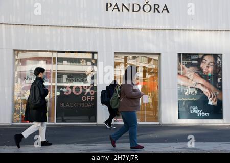 Fußgänger kommen am 26. November 2021 in Tokio, Japan, an einem Schild mit der Aktion „Black Friday“ im Einkaufsviertel von Harajuku vorbei. Einige Geschäfte in Tokio schlossen sich der Black Friday-Schnäppchensaison an, mit Rabatten von 30 % bis 50 % auf ausgewählte Artikel. Quelle: Rodrigo Reyes Marin/AFLO/Alamy Live News Stockfoto