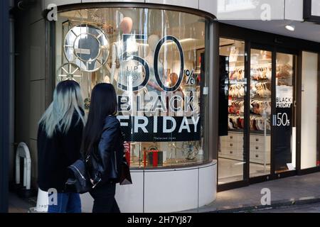 Fußgänger kommen am 26. November 2021 in Tokio, Japan, an einem Schild mit der Aktion „Black Friday“ im Einkaufsviertel von Harajuku vorbei. Einige Geschäfte in Tokio schlossen sich der Black Friday-Schnäppchensaison an, mit Rabatten von 30 % bis 50 % auf ausgewählte Artikel. Quelle: Rodrigo Reyes Marin/AFLO/Alamy Live News Stockfoto