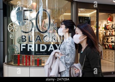 Fußgänger kommen am 26. November 2021 in Tokio, Japan, an einem Schild mit der Aktion „Black Friday“ im Einkaufsviertel von Harajuku vorbei. Einige Geschäfte in Tokio schlossen sich der Black Friday-Schnäppchensaison an, mit Rabatten von 30 % bis 50 % auf ausgewählte Artikel. Quelle: Rodrigo Reyes Marin/AFLO/Alamy Live News Stockfoto