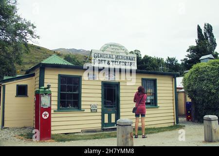 Ein Tourist, der vor dem alten General Merchant, Post & Telegraph Historical Building in Cardrona, Otago, Neuseeland, stampfte. Aufgenommen in Cardrona, New Z Stockfoto