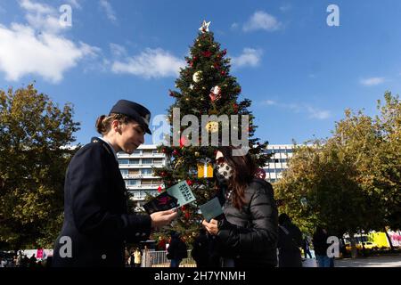 Athen, Griechenland. 25th. November 2021. Eine Polizistin übergibt Passanten am Internationalen Tag zur Beseitigung der Gewalt gegen Frauen in Athen, Griechenland, am 25. November 2021 Flugblätter. Quelle: Marios Lolos/Xinhua/Alamy Live News Stockfoto