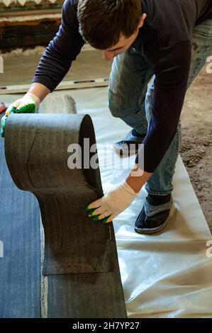 Die Bänder des Dachmaterials, schneidet der Meister die Dachmaterialien aus der Rolle, der Abdichtung des Bodenbelags, den Reparaturarbeiten. Stockfoto