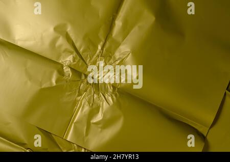 Zerknittertes olivfarbenes Geschenkpapier. Unebene Oberfläche. Abstrakter Hintergrund. Selektiver Fokus. Stockfoto