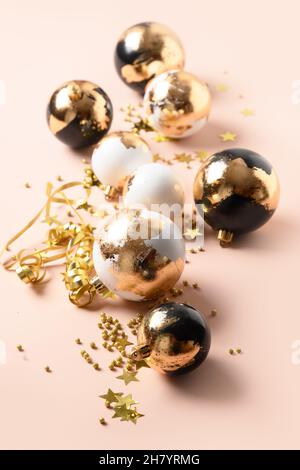 Weihnachtliche weiße und schwarze Kugeln verziert Gold Potal auf rosa. Vertikale Weihnachtskarte. Moderner Luxus-Metallic-Stil. Stockfoto