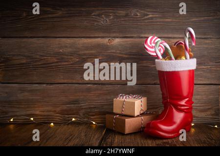 Weihnachtsstiefel mit Süßigkeiten und Geschenken zum Nikolastag am 6th. Dezember. Stockfoto