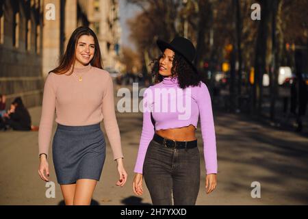 Zwei Freunde verbringen Zeit zusammen, während sie draußen auf der Straße spazieren. Städtisches Konzept. Stockfoto