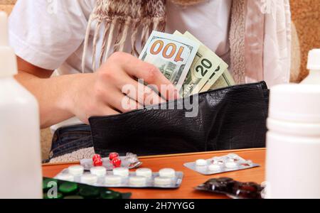 Person, die die Brieftasche mit den Pillen im Vordergrund aus der Nähe überprüft Stockfoto