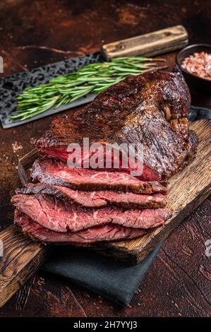 Gebratenes, hängendes, zartes oder in Scheiben geschnittenes Rindersteak auf einem Fleischbrett mit Hackschnitzel. Dunkler Hintergrund. Draufsicht Stockfoto