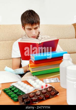 Der junge Mann las die Bücher auf dem Sofa zu Hause mit Pillen auf dem Tisch Stockfoto